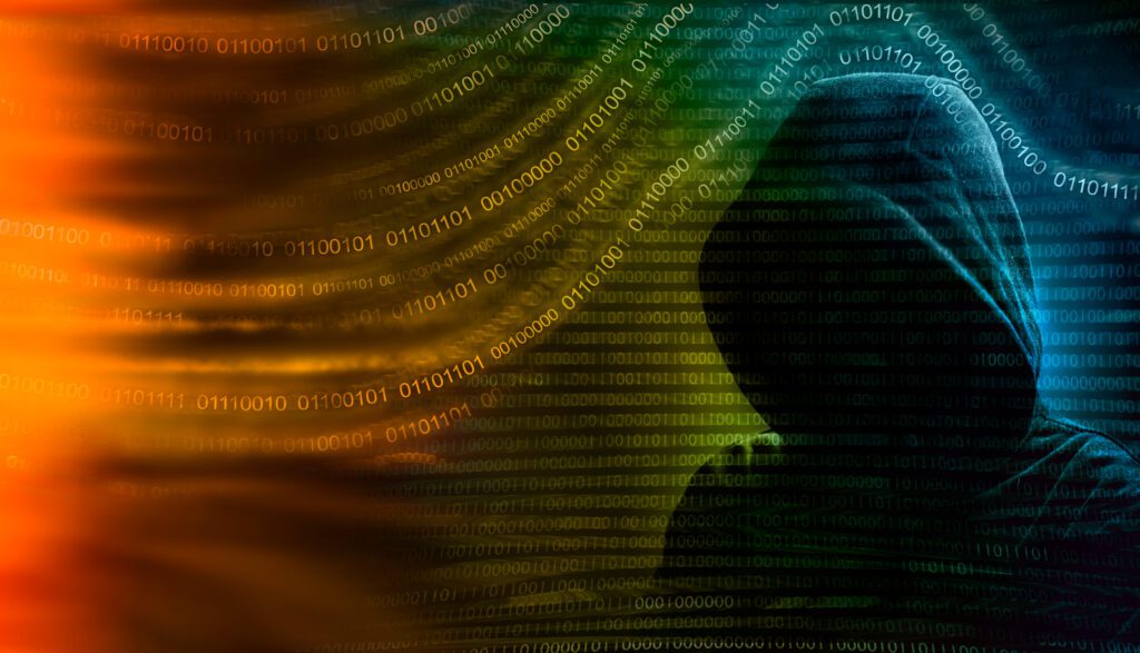 image of a hooded, faceless individual, appearing as a cyberattacker with zeros and ones surrounding the individual
